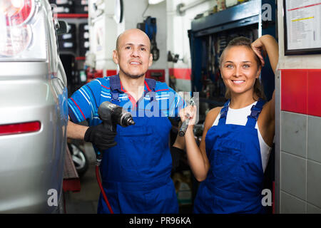 Sourire joyeux deux mécaniciens unis dans la réparation automobile workshop Banque D'Images