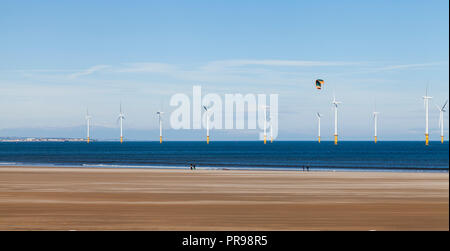 Un jour de vent sur la plage à Redcar,Angleterre,UK avec les éoliennes en arrière-plan et un kite surfer de se préparer à partir dans la mer Banque D'Images