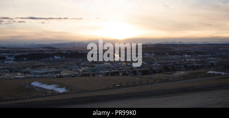 Donnant sur la ville de Cochrane, dans un coucher de soleil d'hiver avec les usines de la vapeur contre les Rocheuses. Banque D'Images