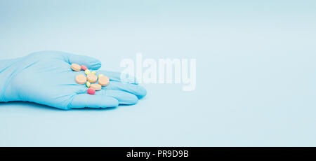 Femme main tenant différents médicaments comprimés avec fond bleu. Banque D'Images