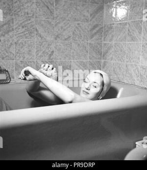 Prendre un bain 1940. Eivor actrice Landström, 1919-2004, photographié ici à la maison, avoir une baignoire. Elle porte un chapeau de protection pour empêcher les cheveux de devenir humide. Elle utilise une éponge de bain dans la baignoire. La Suède d'août 1940. Kristoffersson Photo ref 158-25