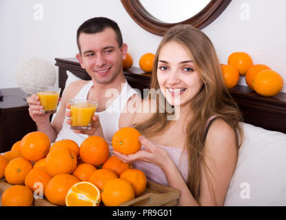 Jeune homme européen et petite amie de boire du jus d'orange frais au lit Banque D'Images