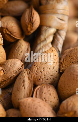 Macro d'amandes biologiques sains cueillis dans leur coquille image plein cadre avec un vieux paniers en osier vertical avec focus sélectif en arrière-plan et fo Banque D'Images