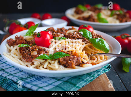 Close-up of Italian spaghetti avec sauce tomate, parmesan et basilic frais sur le dessus, sur fond sombre Banque D'Images