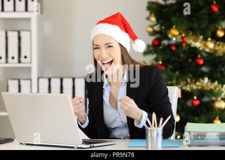 Heureux office worker looking at camera dans l'époque de Noël avec un arbre dans l'arrière-plan Banque D'Images