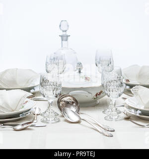 Manger amende : blanc motif floral de Chine dîner organisé sur une table avec nappe vintage et napikins, verres en cristal. Focus sélectif. Banque D'Images