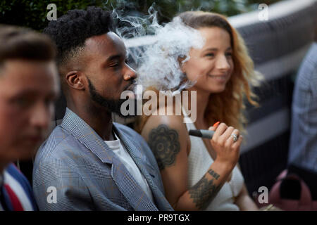 Les gens qui fument à l'aide de vape happing pens à Manchester Banque D'Images