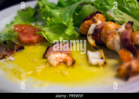 Brochettes de crevettes et de calmars cuits sur une assiette avec la sauce et salade Banque D'Images