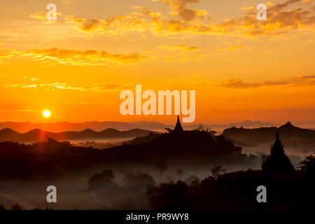 Le lever du soleil, et morning mist ci-dessous une pagode dans les collines à l'extérieur de Mrauk U ville. Côte ouest du Myanmar Banque D'Images