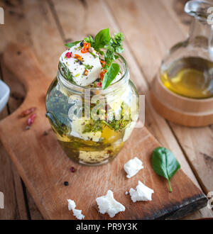 Close-up de Feta mariné dans l'huile d'olive, les herbes et les flocons de poivron rouge sur fond de bois Banque D'Images