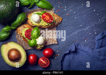 Bruschettas avec pain de seigle, le guacamole, tomates et mozzarella Banque D'Images