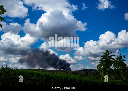 Fumée noire énorme d'un gigantesque feu de camion en feu le transport des composants de la fenêtre en plastique vu de loin dans un beau paysage d'été le 10 août 2018. Banque D'Images