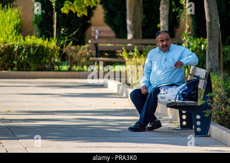 Un homme s'assit sur un banc à Shiraz, Iran Banque D'Images