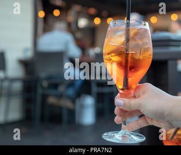 La main de femme tenant un Spritz plein un verre dans un bar Banque D'Images