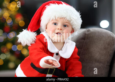 Cute baby wearing santa claus costume sur un canapé à la maison à Noël Banque D'Images