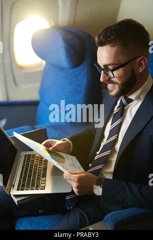 Jeune homme d'affaires travaillant en avion Banque D'Images