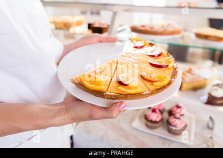 Vente Baker woman putting des tartes et des gâteaux sur l'affichage Banque D'Images