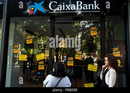 Barcelone, Espagne. 06Th Oct, 2018. Les passants se tenir en face d'une banque à laquelle des affiches ont été apposées par divers groupes du Comité pour la défense de la République, une association qui défend le référendum sur l'indépendance de la Catalogne. 01.10.2018 marque le premier anniversaire de l'indépendance du référendum controversé crise espagnole région Catalogne. Crédit : Nicolas Carvalho Ochoa/dpa/Alamy Live News Banque D'Images