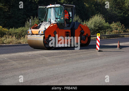 L'exécution de travaux de réparation : rouleau d'asphalte chaud et en appuyant sur l'empilage de laïcs de l'asphalte. La réparation de la machine. Banque D'Images