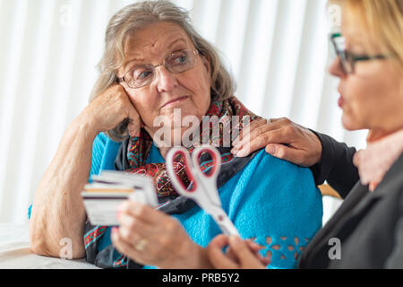 Le Consultant financier Remise des ciseaux pour Senior Lady Holding Credit Cards. Banque D'Images