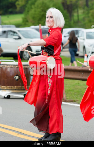 Une taille de l'équipe chinoise du tambour, vêtus de couleurs vives en costume traditionnel, fonctionne à un festival local. Banque D'Images