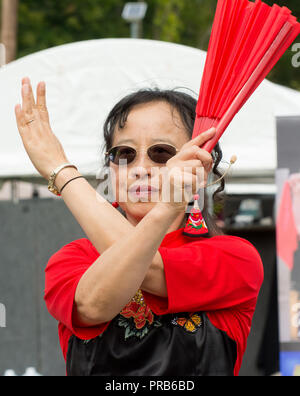 Une taille de l'équipe chinoise du tambour, vêtus de couleurs vives en costume traditionnel, fonctionne à un festival local. Banque D'Images