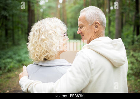 Vue arrière du couple à l'embrasser dans la forêt sur journée d'été Banque D'Images