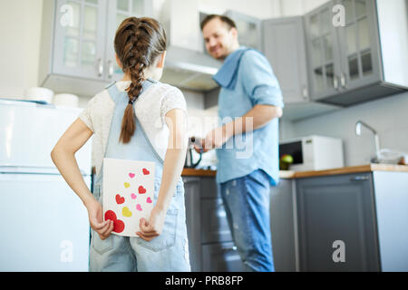 Jeune fille se cacher carte de souhaits pour son père derrière retour avant le féliciter pour le jour de père Banque D'Images