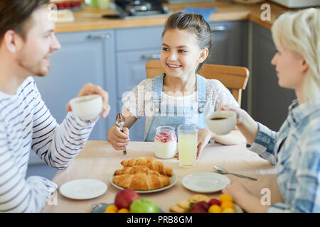 Petite fille heureuse à la recherche de son père pendant le petit-déjeuner servi par le tableau Banque D'Images