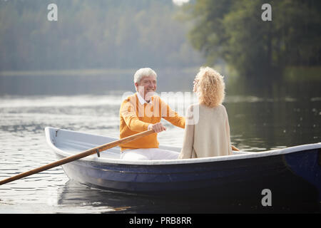 Cheerful excité romantic man en chandail jaune tomber en amour avec une belle dame aux cheveux bouclés bateau à rames et souriant à copine whil Banque D'Images