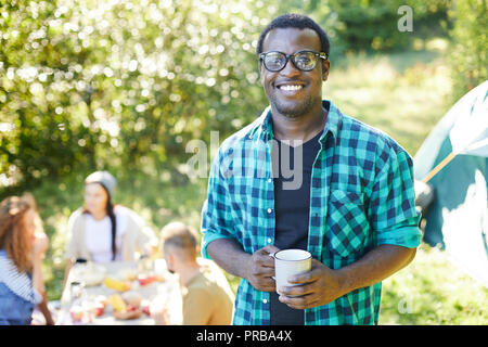 Jeune homme afro-américains avec plateau debout devant la caméra tout en profitant de voyage avec ses amis Banque D'Images