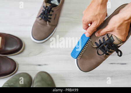 L'homme le nettoyage et le polissage de souliers en cuir avec pinceau sur fond de bois Banque D'Images