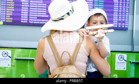 Jeune mère embrassant son petit garçon Playing with toy airplane in airport Banque D'Images