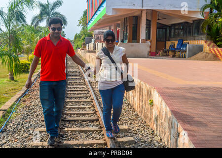 Le jeune couple en train de marcher sur une voie de chemin de fer. Traveler s'amusant à la gare tenant la main garder l'équilibre. Married Couple holding hands walking Banque D'Images