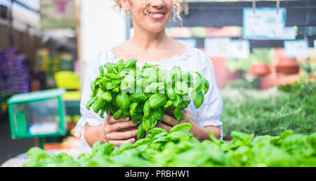 Jeune femme aux cheveux bouclés blonds choisit un semis de basilic dans un magasin. Concept de soins et de passion pour la nature Banque D'Images