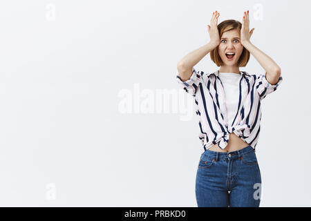 Femme criant de choc, la réflexion sur les examens qui arrive à la cheville. Portrait of a souligné tree nerveux Chemisier rayé et jeans, tenant les mains sur la tête et regardant la caméra, avec anxiété Banque D'Images