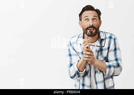 Stratège charmant penser à nouveau plan. Portrait de l'homme sympathique rêve scientifique dans serra shirt, mordre de RIM lors de l'utilisation de verres de l'imagination et le regard jusqu'à trouver d'idée Banque D'Images