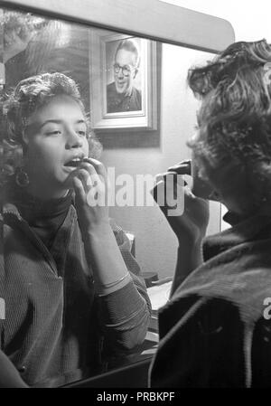 Le Maquillage dans les années 1950. Une jeune femme se tient debout devant un miroir appliquer le rouge à lèvres. Chanteur photo Lill-Babs Svensson, 1938-2018 dans le dressing de Bal Palais de Stockholm 1954. Ref 11-15-7 Banque D'Images