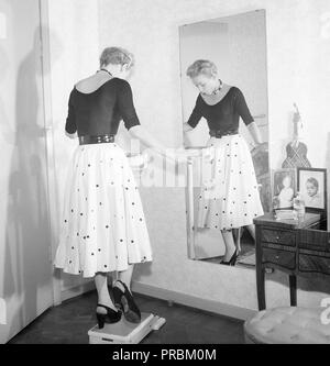 La mode des années 1950. Une jeune femme se tient debout sur une jambe sur l'échelle d'essayer d'être aussi léger que possible. Actrice photos AnnaLisa Ericson, 1913-1911. La Suède des années 1950. Kristoffersson Photo ref BM74-10 Banque D'Images