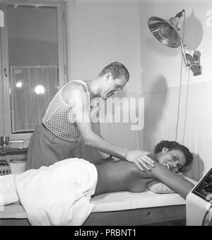 Soins de beauté dans les années 1950. Une jeune femme est d'avoir un massage par un homme de la manipulation du traitement. Il porte la sorte très spéciale de t-shirt avec le tricot comme un filet, principalement pour être utilisée sous votre chemise. Suède 1951. Kristoffersson Photo Ref ÊTRE103-3 Banque D'Images