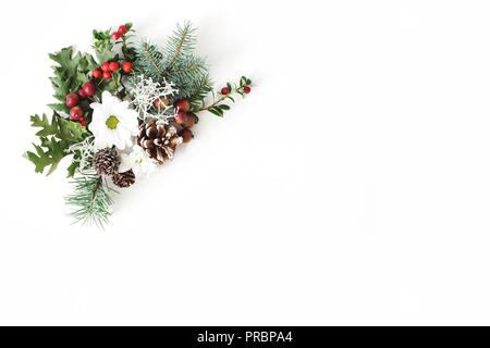 Composition florale de fête de Noël. Cônes de pin, sapin, branches d'arbre, les feuilles de chêne rouge, de baies et de fleurs de chrysanthème rowan sur arrière-plan du tableau blanc. Coin décoratif. Mise à plat, vue du dessus. Banque D'Images