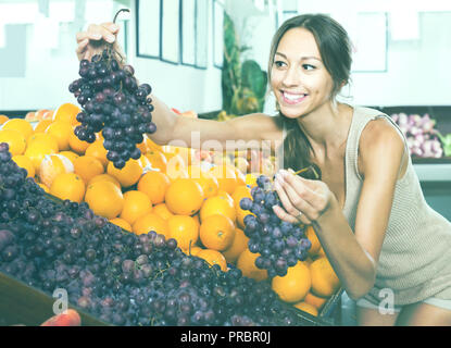 Jeune femme positive Le choix du client en magasin fruits raisins Banque D'Images