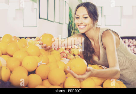 Femme Russe smiling customer picking oranges sur le marché aux fruits Banque D'Images