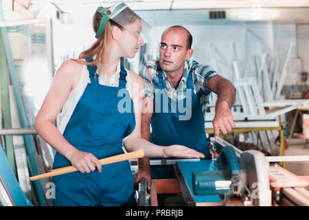 Aider les travailleurs expérimentés de diligence friendly smiling girl dans le travail sur scie circulaire en plastique à l'usine de windows Banque D'Images