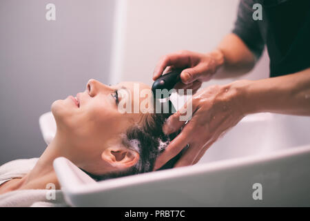 Young woman getting nouvelle coiffure coiffure professionnel au saloon. Coiffure est en massant son chef. Banque D'Images