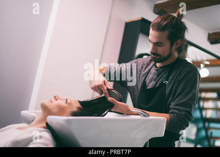 Young woman getting nouvelle coiffure coiffure professionnel au saloon. Banque D'Images