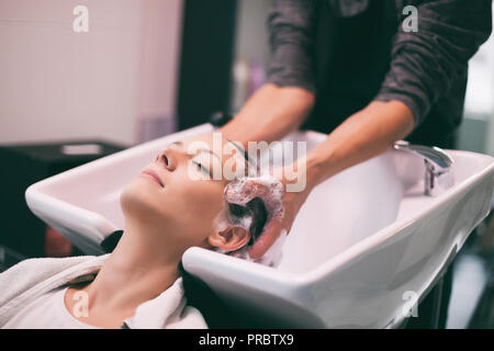 Young woman getting nouvelle coiffure coiffure professionnel au saloon. Coiffure est en massant son chef. Banque D'Images