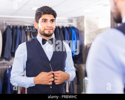 Homme cherche sur image choisie devant le miroir dans la boutique. Banque D'Images