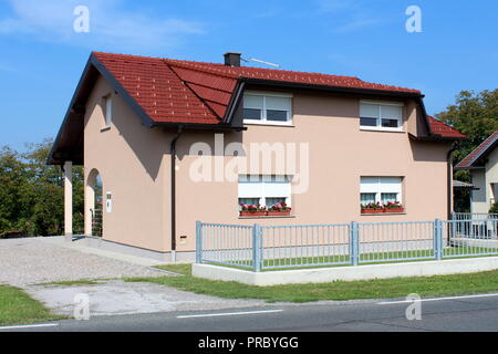 Entièrement rénové petite maison de famille de banlieue avec nouvelle façade, fenêtres blanches avec des fleurs fraîches, de nouvelles tuiles et gouttières, entouré de métal gris Banque D'Images