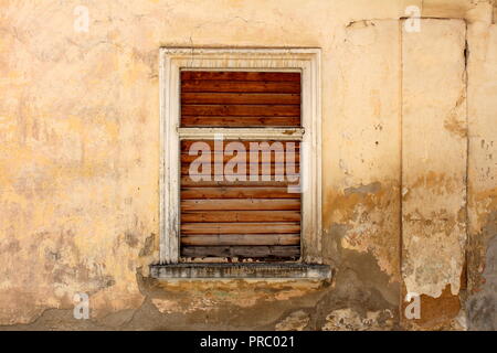 Cadre en bois vitrée avec stores en bois ancienne ferme abandonnée sur maison en pierre avec façade fissurée délabrée sur chaude journée ensoleillée Banque D'Images